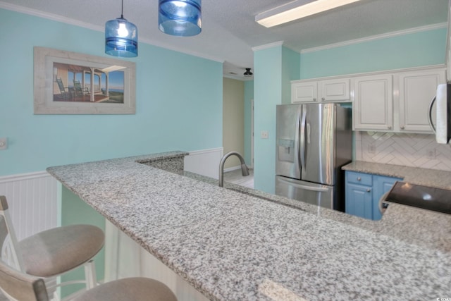 130 Scotch Broom Dr Unit H-103, Little River, SC 29566 - kitchen with hanging light fixtures, stainless steel appliances, ornamental molding, a wainscoted wall, and white cabinetry