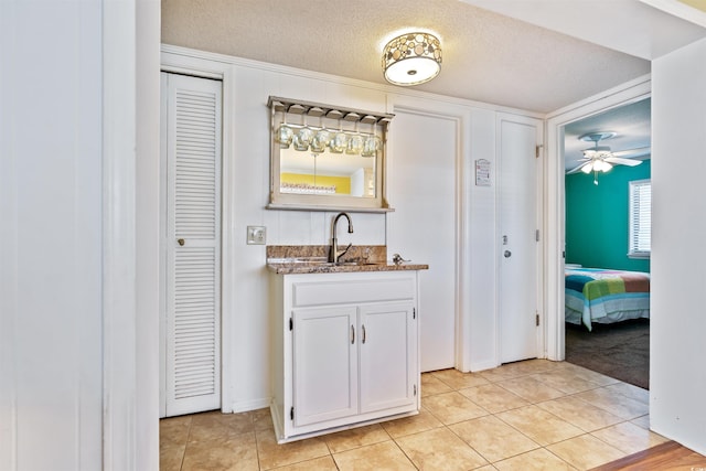 interior space featuring indoor wet bar, a sink, a textured ceiling, and light tile patterned floors