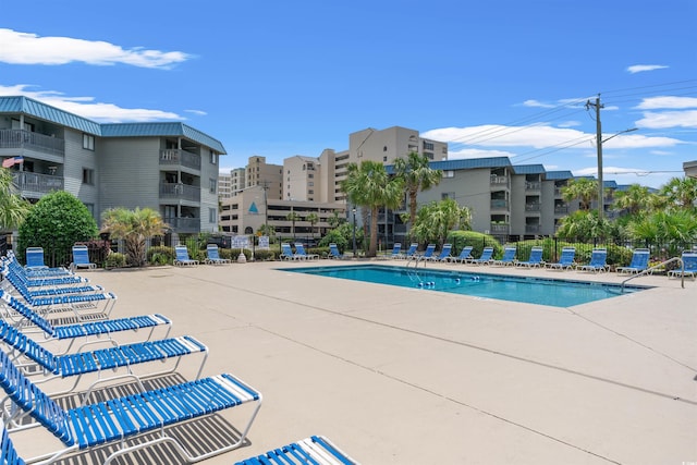 community pool with a patio area and fence