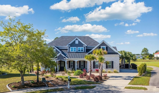 craftsman-style house featuring covered porch, a standing seam roof, metal roof, a front yard, and concrete driveway