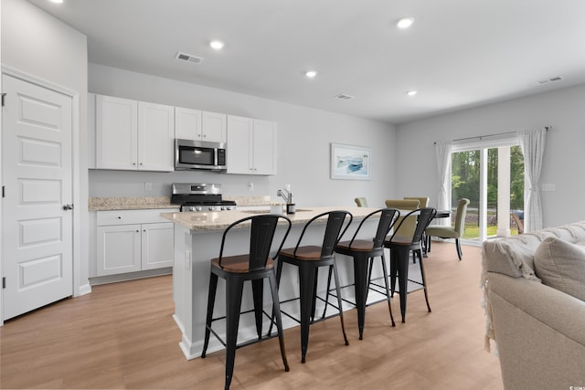 109 River Vista Way, Myrtle Beach, SC 29588 - kitchen with stainless steel appliances, open floor plan, an island with sink, white cabinets, and a kitchen bar