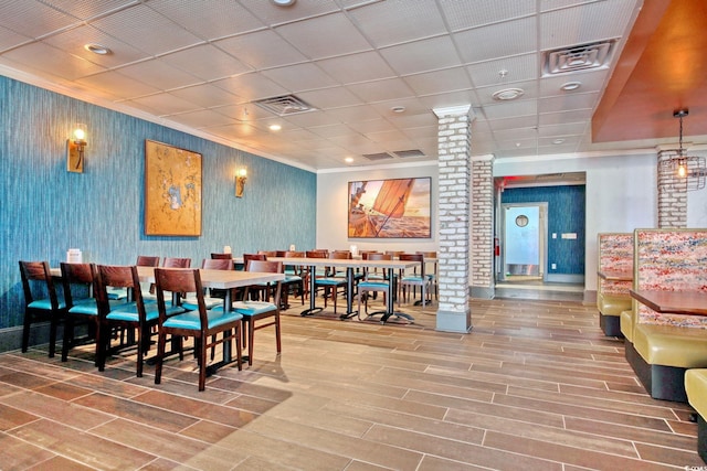 7200 Ocean Blvd N Unit 664, Myrtle Beach, SC 29572 - dining space with decorative columns, wood finished floors, wallpapered walls, a paneled ceiling, and ornamental molding