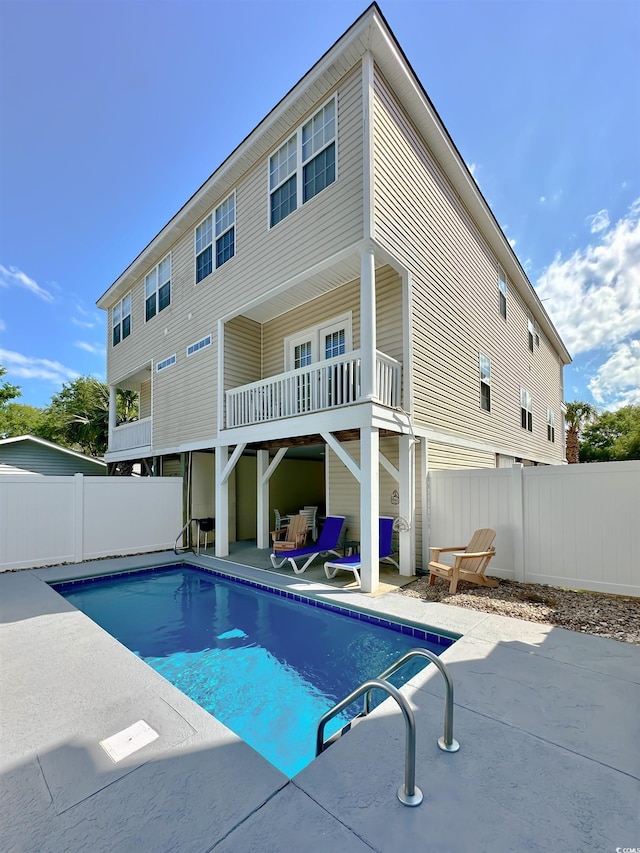 rear view of property with fence, a patio area, and a balcony