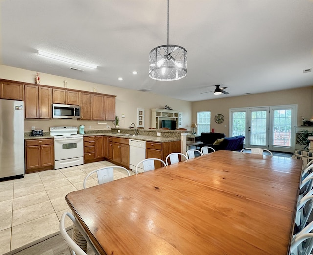 kitchen with white appliances, a sink, brown cabinets, and a textured ceiling