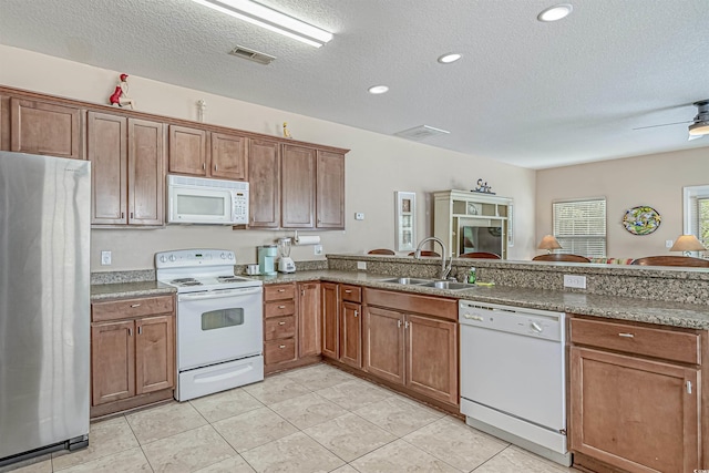 118A 6th Ave N, Surfside Beach, SC 29575 - kitchen featuring white appliances, a sink, a textured ceiling, a peninsula, and brown cabinetry