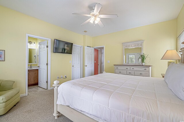 bedroom with carpet floors, a sink, baseboards, ensuite bath, and a ceiling fan