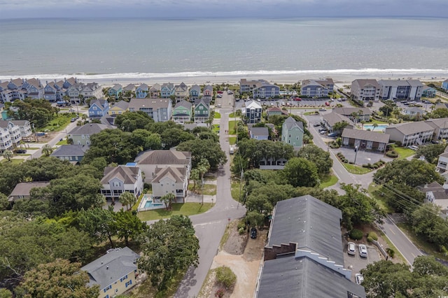aerial view of property's location featuring waterfront with a beach and nearby suburban area