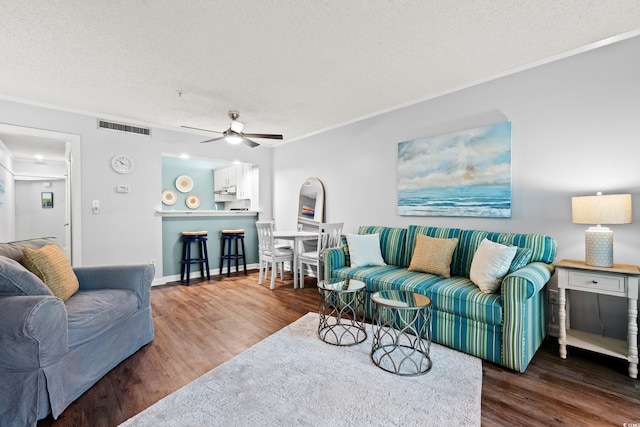 living area with a ceiling fan, a textured ceiling, visible vents, and wood finished floors