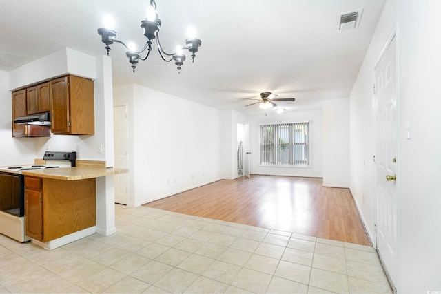 kitchen with white electric stove, under cabinet range hood, light countertops, ceiling fan with notable chandelier, and visible vents
