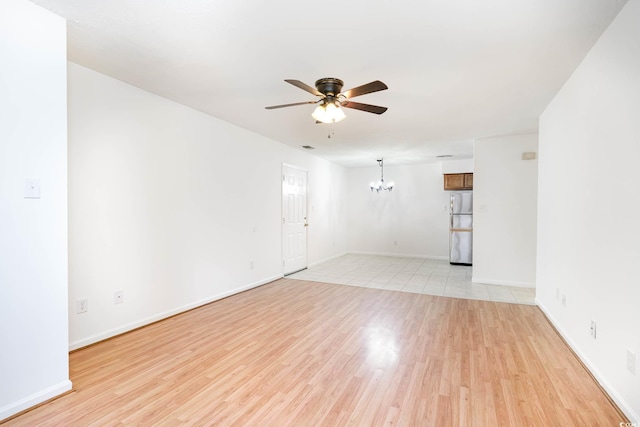 spare room with baseboards, light wood-style flooring, and ceiling fan with notable chandelier