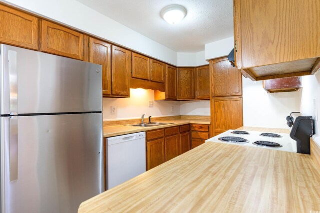 kitchen featuring a sink, brown cabinets, and white appliances