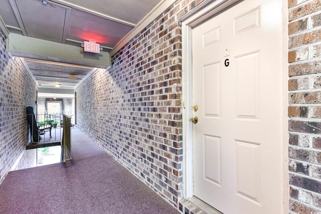 hall featuring brick wall