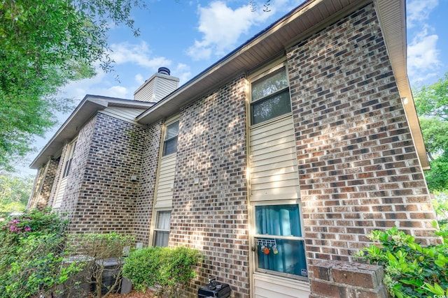 view of home's exterior with a chimney and brick siding