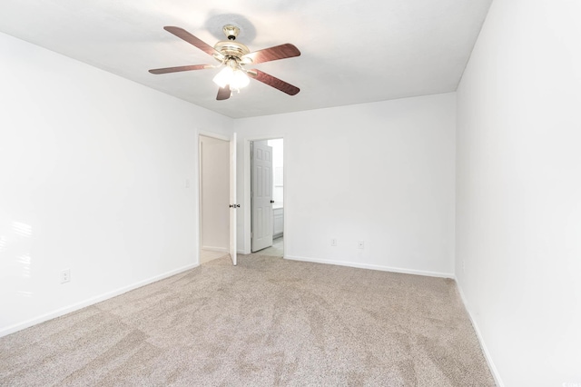 carpeted empty room with a ceiling fan and baseboards