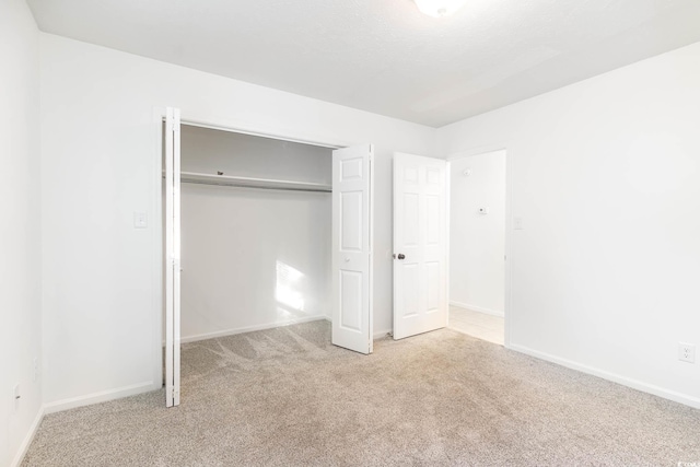 unfurnished bedroom featuring a closet, baseboards, and carpet floors