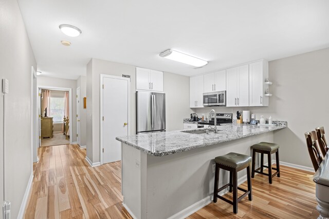 1204 River Oak Dr Unit 25-A, Myrtle Beach, SC 29579 - kitchen with appliances with stainless steel finishes, a peninsula, a sink, white cabinets, and a breakfast bar area