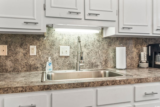 kitchen featuring dark countertops, white cabinetry, tasteful backsplash, and a sink