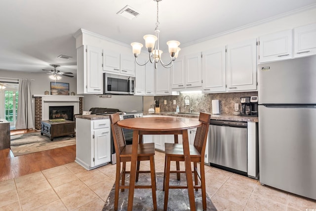 kitchen featuring a sink, light tile patterned flooring, visible vents, white cabinetry, and appliances with stainless steel finishes