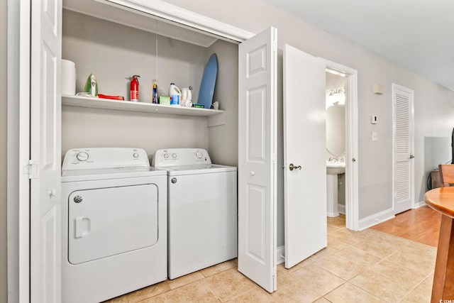 laundry room featuring light tile patterned floors, washer and dryer, laundry area, and baseboards