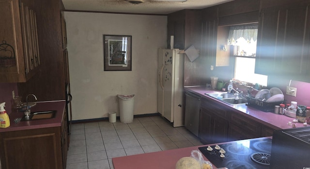 kitchen featuring a sink, stainless steel dishwasher, light tile patterned flooring, and freestanding refrigerator
