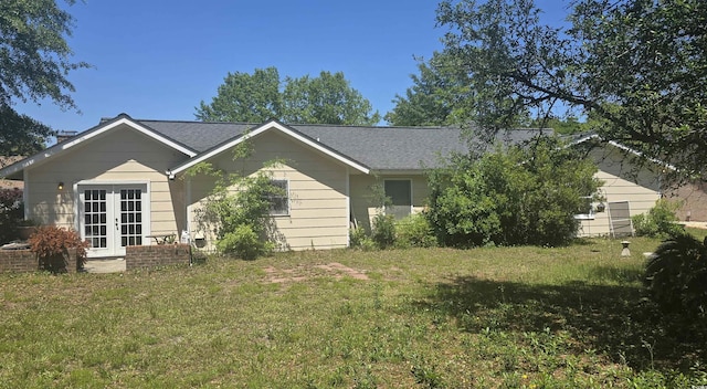 exterior space with french doors, roof with shingles, and a lawn