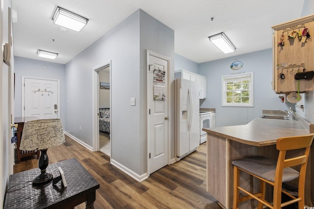 2090 Cross Gate Blvd Unit 202, Surfside Beach, SC 29575 - kitchen featuring white appliances, a sink, dark wood finished floors, a peninsula, and a kitchen bar