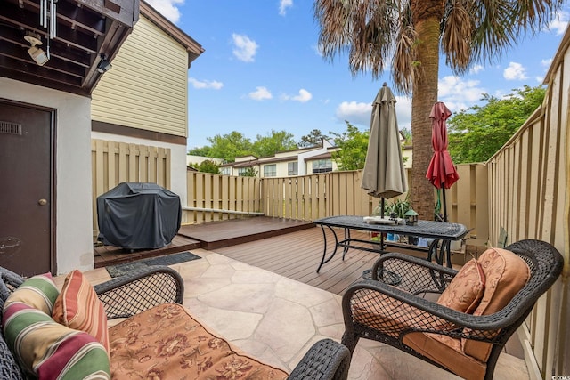 view of patio / terrace featuring grilling area, a deck, outdoor dining space, and a fenced backyard