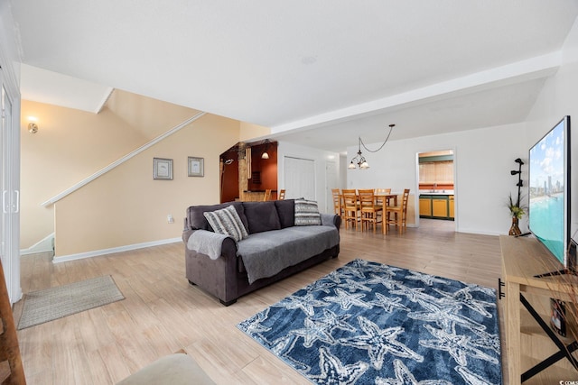 living area with baseboards, stairs, wood finished floors, and a notable chandelier