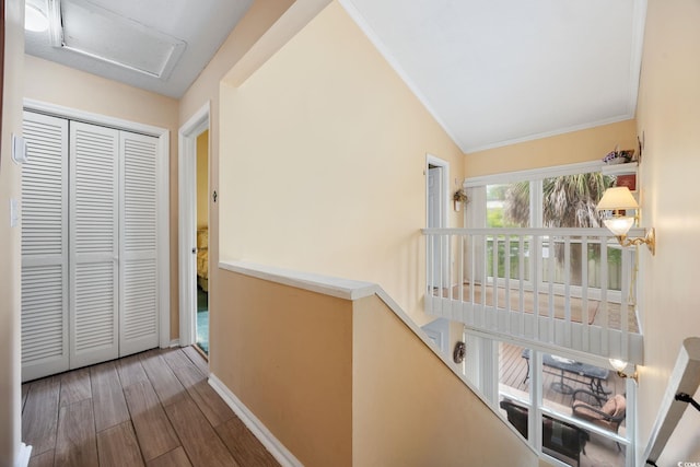 corridor featuring baseboards, ornamental molding, attic access, and wood finished floors