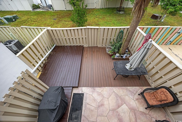 wooden terrace featuring central air condition unit, a yard, and a fenced backyard