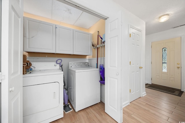 laundry area featuring visible vents, light wood-style flooring, cabinet space, and washing machine and dryer