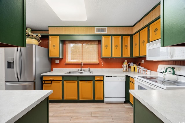 kitchen featuring visible vents, a sink, white appliances, and light countertops