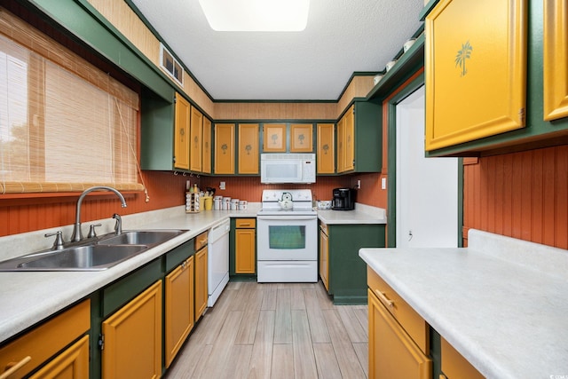 kitchen featuring white appliances, a textured ceiling, a sink, and light countertops