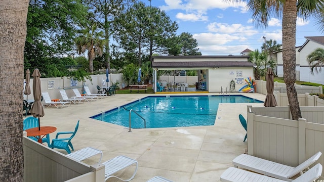 pool featuring an outdoor structure, a fenced backyard, and a patio area