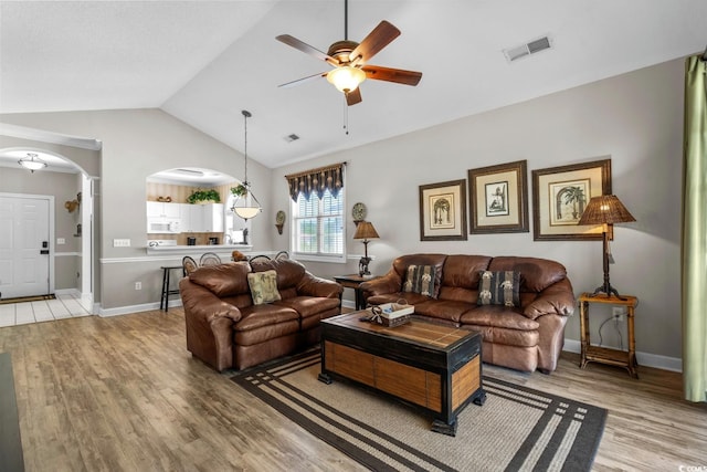 living room featuring a ceiling fan, visible vents, arched walkways, wood finished floors, and lofted ceiling