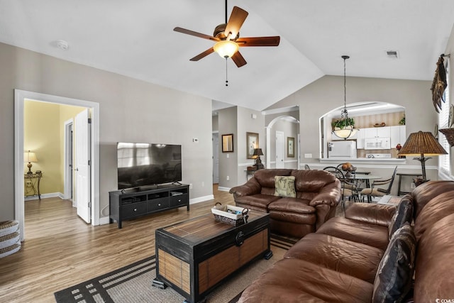living area featuring visible vents, wood finished floors, ceiling fan, arched walkways, and vaulted ceiling