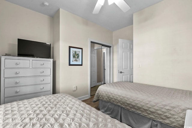 bedroom with a closet, dark wood-style flooring, lofted ceiling, baseboards, and a ceiling fan