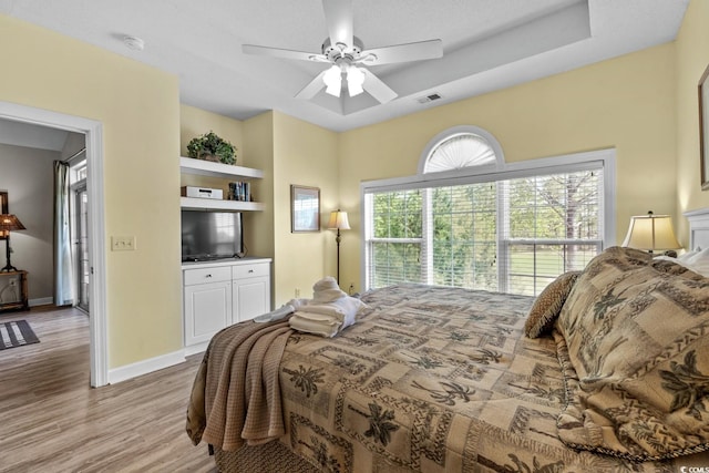 bedroom featuring baseboards, ceiling fan, light wood-style flooring, and visible vents