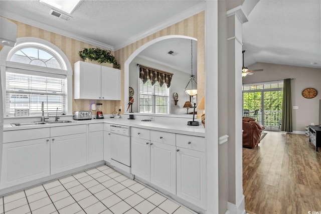 kitchen featuring a textured ceiling, visible vents, white dishwasher, arched walkways, and a sink
