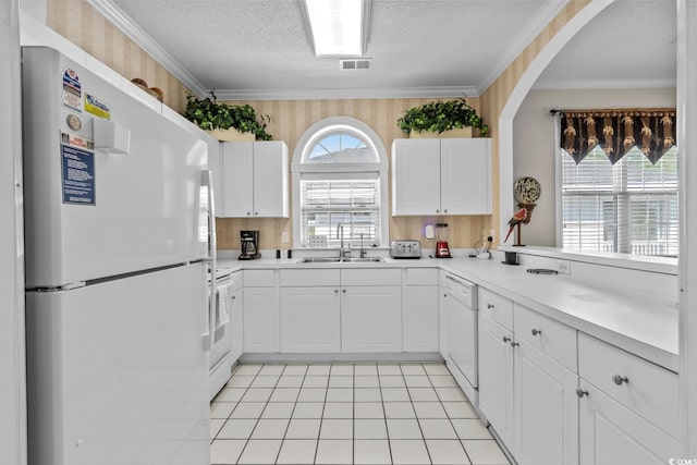 kitchen featuring a sink, white cabinets, white appliances, and visible vents