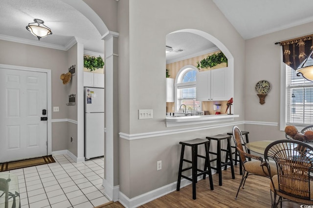 entryway with crown molding, arched walkways, baseboards, and visible vents