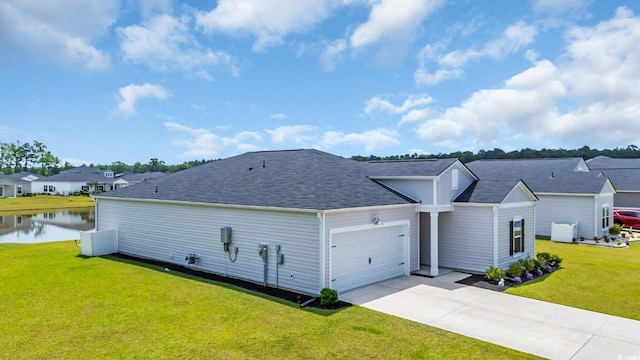 exterior space with a lawn, a water view, an attached garage, and concrete driveway