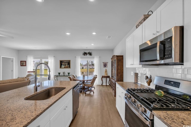 kitchen with plenty of natural light, a sink, appliances with stainless steel finishes, and white cabinets
