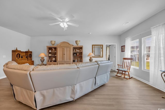 living room featuring baseboards, ceiling fan, and light wood-style flooring