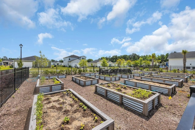 view of home's community with fence, a residential view, and a vegetable garden