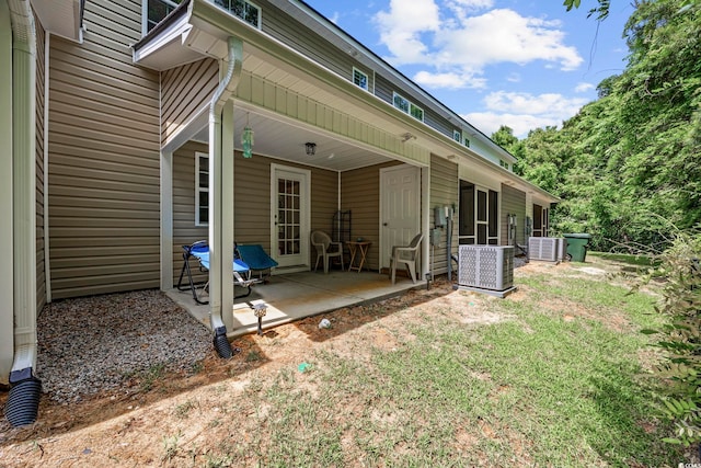 rear view of house with central air condition unit, a patio, and a yard