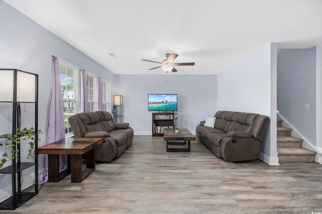 living area featuring visible vents, wood finished floors, baseboards, ceiling fan, and stairway