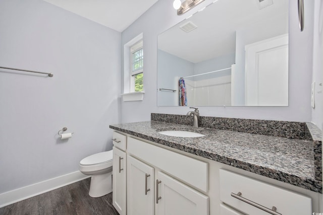 bathroom featuring visible vents, wood finished floors, baseboards, vanity, and toilet