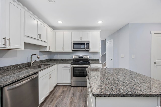 kitchen with a kitchen island, dark wood-style floors, white cabinetry, a sink, and stainless steel appliances