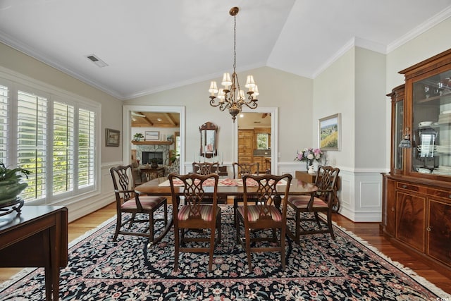 741 Tuckers Rd, Pawleys Island, SC 29585 - dining space featuring wood finished floors, a fireplace, a chandelier, a wainscoted wall, and ornamental molding